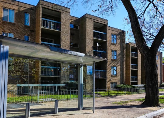 an apartment building with a bus stop in front of it