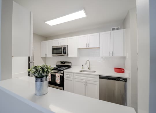 A white kitchen with a stove, oven, microwave, and cabinets.