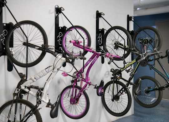 A collection of bicycles are hanging on a wall.