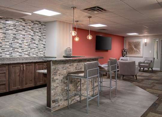 A bar area with a stone counter and metal chairs.