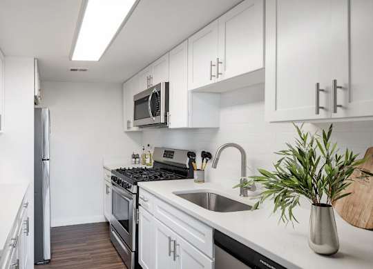 A kitchen with white cabinets and a stainless steel refrigerator.