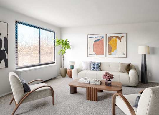 A living room with a white couch, a wooden coffee table, and a large window.