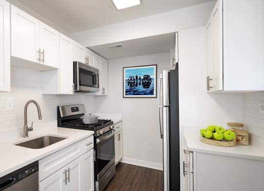 A kitchen with white cabinets and a fridge.