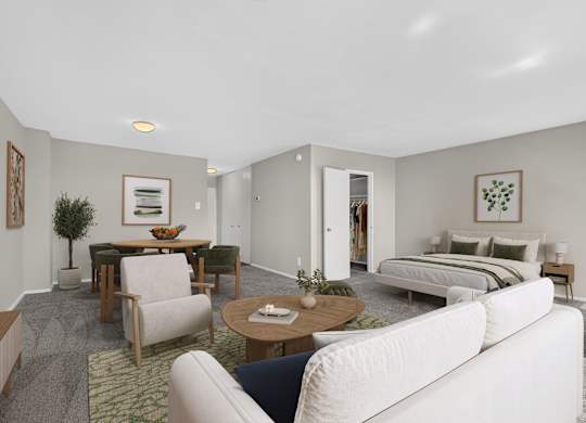 A living room with a white couch, a coffee table, and a bed in the background.