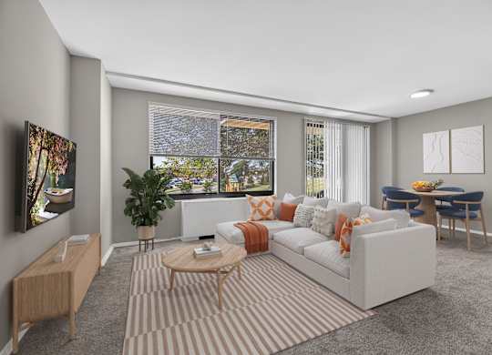 A living room with a white sofa, a wooden coffee table, and a TV on the left side.