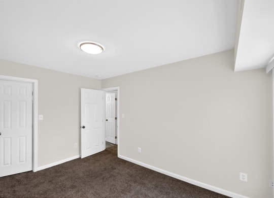 an empty room with a carpeted floor and white doors