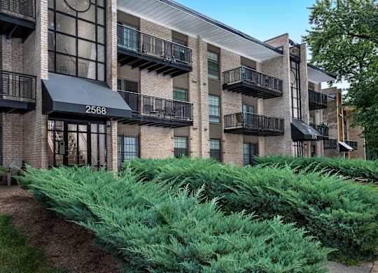 an exterior view of a brick apartment building with green plants
