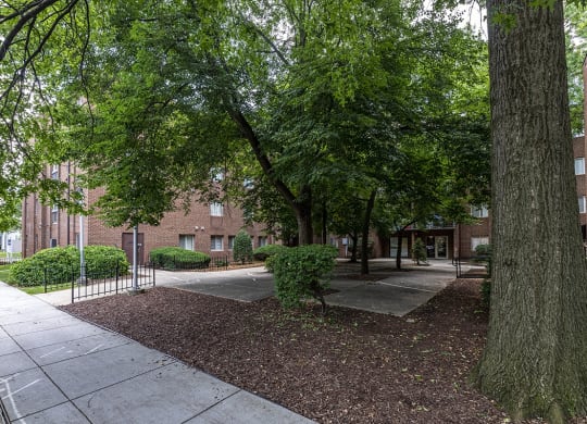 a sidewalk and trees in front of a brick building