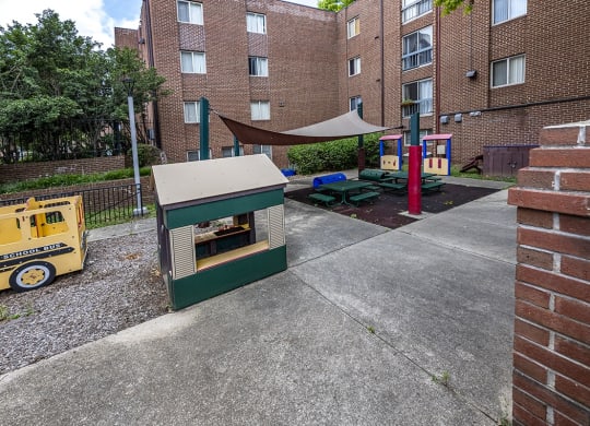 a play area with a hot dog cart in front of a brick building