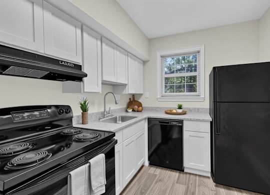 Modern kitchen with white cabinetry and black appliances at Highland Ridge Apartments, Maryland
