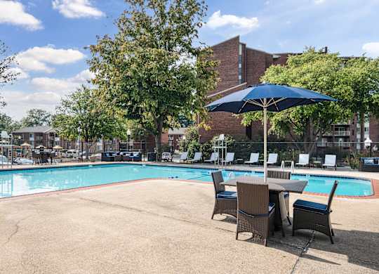 A pool with chairs and an umbrella in the foreground.