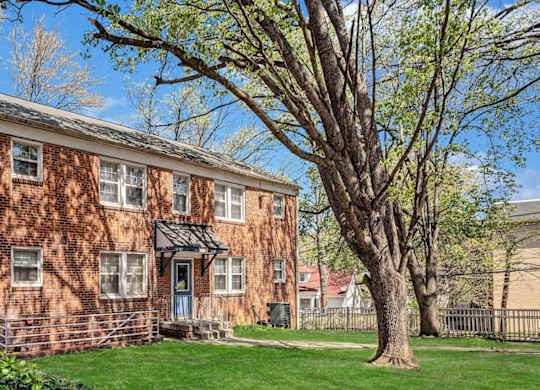 Brick apartment building with mature trees at Highland Ridge Apartments, Capitol Heights, Maryland