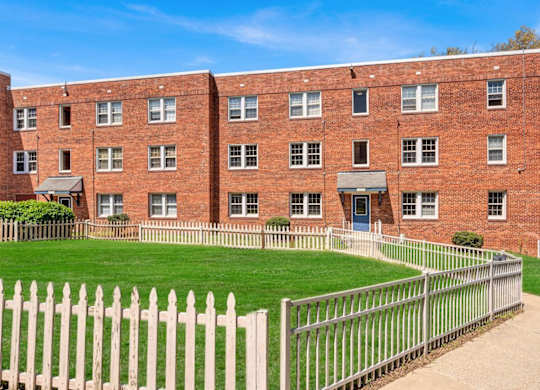 Red brick apartment building with white picket fence at Highland Ridge Apartments, Maryland