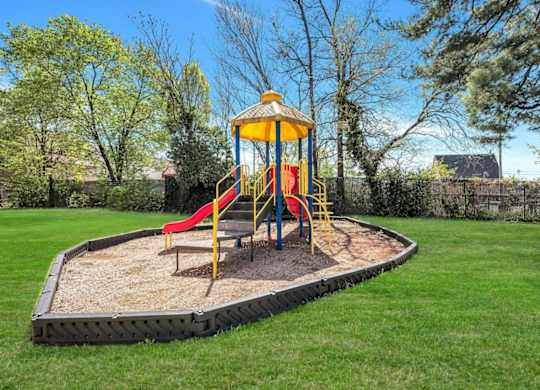 Playground with colorful equipment and gravel surface at Highland Ridge Apartments, Maryland, 20743