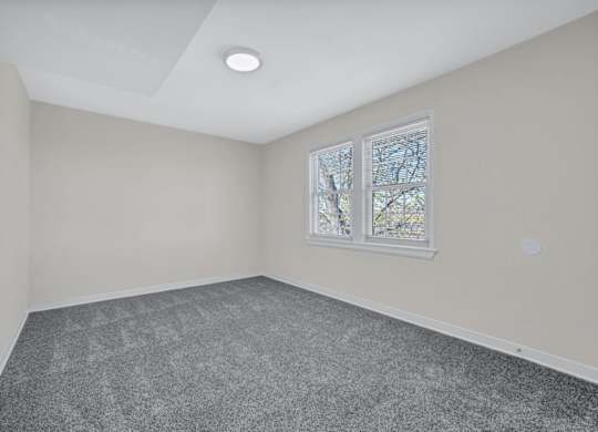 Empty bedroom with gray carpet and window blinds at Highland Ridge Apartments, Capitol Heights, MD 20743