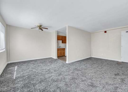 Open concept living room with adjacent kitchenette at Highland Ridge Apartments, Capitol Heights, Maryland