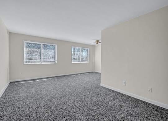 Empty carpeted living room with two windows at Highland Ridge Apartments, Capitol Heights