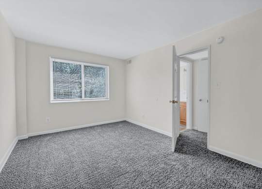 Empty bedroom with gray carpet and closet at Highland Ridge Apartments, Maryland
