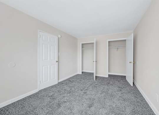 Empty bedroom with dual closets and carpet at Highland Ridge Apartments, Maryland, 20743
