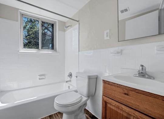 Bathroom with white subway tile and wood vanity at Highland Ridge Apartments, Capitol Heights, MD 20743