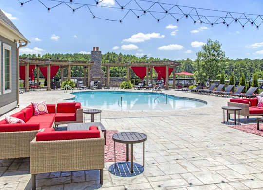 a swimming pool with red chairs and tables around it at Century Lakeshore Crossings, Birmingham, 35211