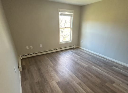 an empty living room with hardwood flooring and a window at Briarcliff at Quechee Apartments, Quechee, Vermont