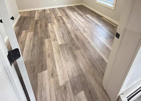 an empty room with wood floors and a window at Briarcliff at Quechee Apartments, Quechee, VT