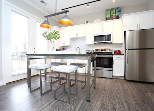 a kitchen with stainless steel appliances and a bar with three stools at Century Baxter Avenue, Louisville, 40204