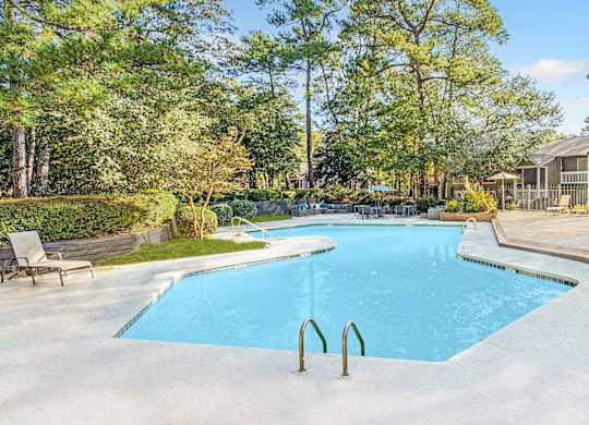 A large blue swimming pool surrounded by trees and a wooden deck. at Grove at St. Andrews, Columbia, SC