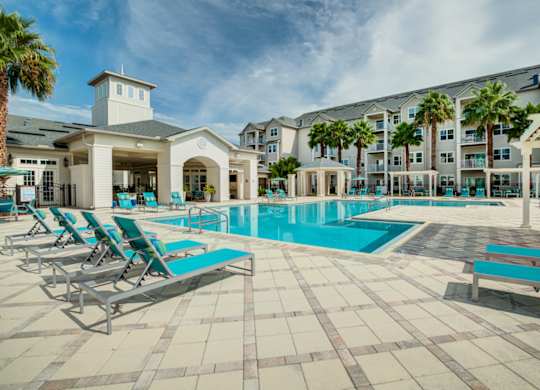 a swimming pool with chaise lounge chairs and a building in the background  at Century Avenues, Lakeland
