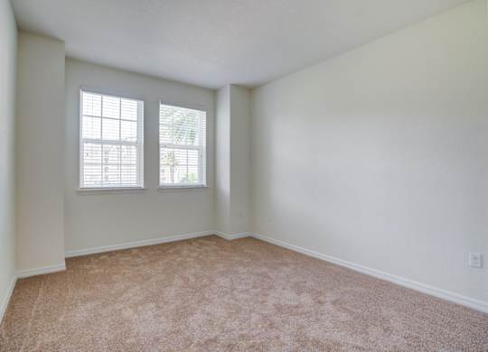 a bedroom with two windows and a carpeted floor  at Century Avenues, Lakeland, FL
