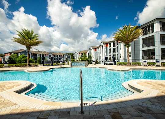 a large swimming pool with apartments in the background at Century Dunes Apartments, Deland