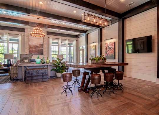 a large living room with a wooden floor and a table with stools at Century New Holland, Gainesville, GA