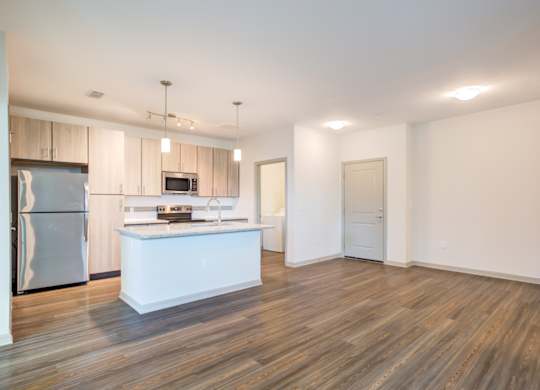 an empty living room with a kitchen with stainless steel appliances at Century Town Center, Florida