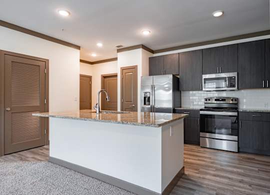 A modern kitchen with a white island and stainless steel appliances. at Century Belmont Station, Louisville, 40243