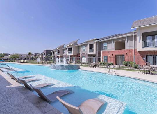 our apartments offer a swimming pool with chairs and a fountain at Century Palm Bluff, Portland, TX, 78374