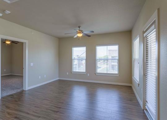 an empty living room with a ceiling fan and windows at Century Palm Bluff, Portland