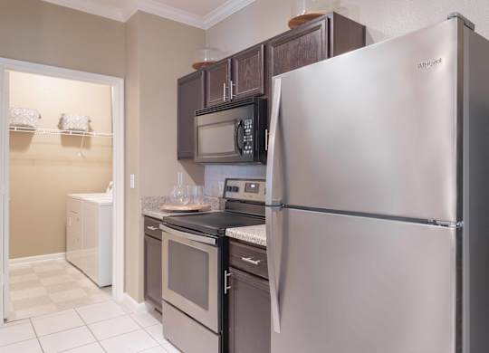a kitchen with stainless steel appliances and black cabinets at Century South Shore, League City, Texas