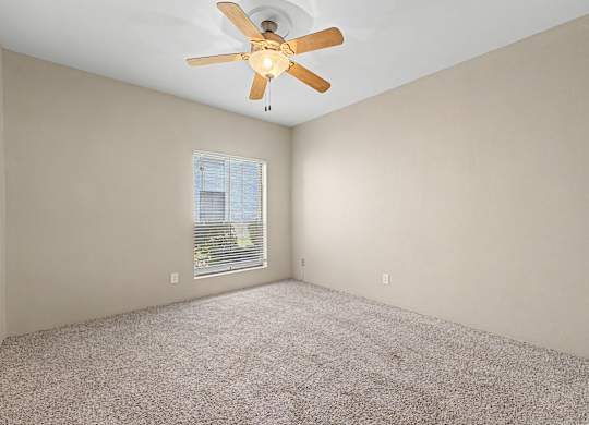 A room with a ceiling fan and a window with blinds.