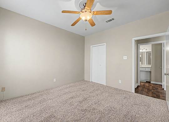 A room with a ceiling fan and carpeted floor.