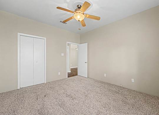 A room with a ceiling fan and carpeted floor.