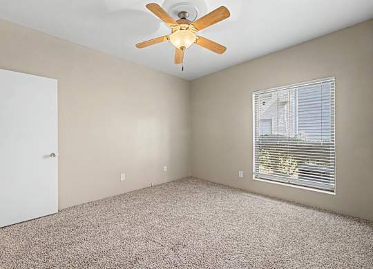 A room with a ceiling fan and a window with blinds.