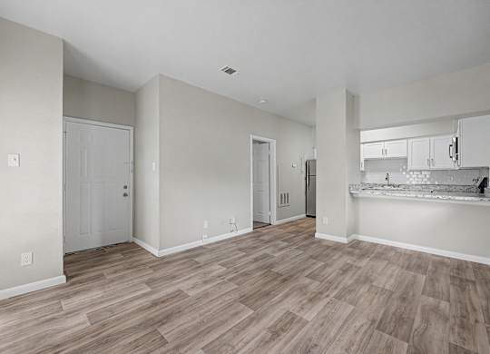 A spacious room with wooden flooring and white walls.