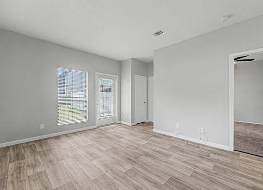 A room with light wood flooring and white walls.