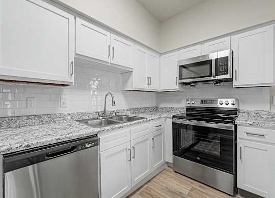 A kitchen with white cabinets and a granite countertop.