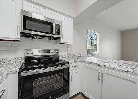 A kitchen with a black oven and microwave above a granite countertop.