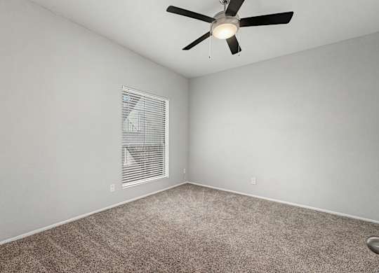 A room with a ceiling fan and carpeted floor.