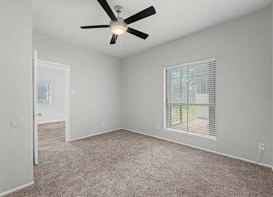 A room with a ceiling fan and carpeted floor.