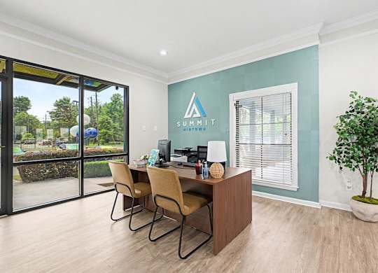 A room with a desk and chairs with Summit sign on the wall.