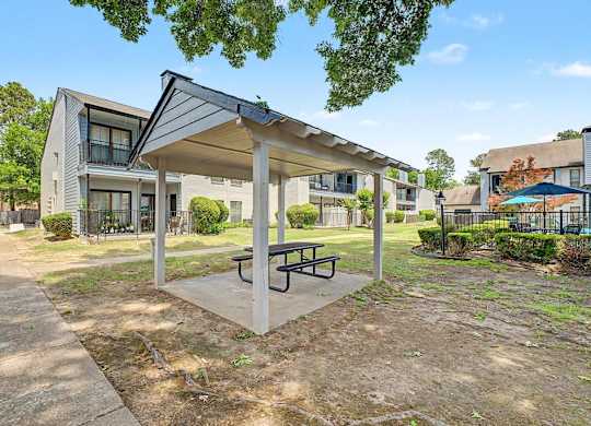 A covered picnic table is in the foreground of a residential area.